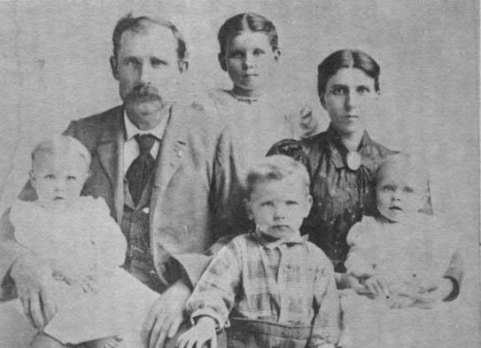Charlie B. Ensor, standing by his grandfather, William Asbury Ensor, who is seated next to his wife, Naomi Florilla Huddleston Ensor.