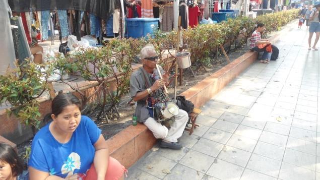 A man who plays music on a flute in Bangkok to earn a living.