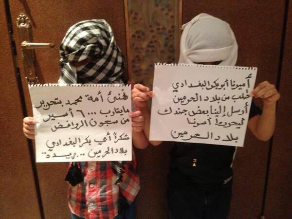 Two Saudi children hold placards celebrating the ISIS jailbreaks in Baghdad.