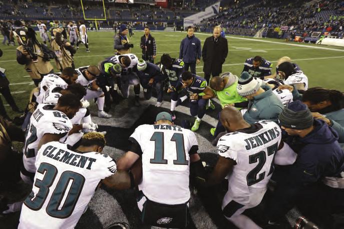 Seattle Seahawks and Philadelphia Eagles players huddle on bended knee to